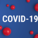 Inscription COVID-19 on blue background with red strain model of coronavirus